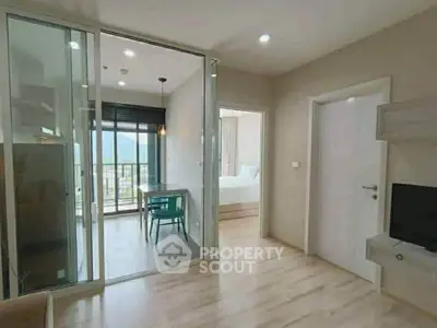Modern apartment interior with glass partition, wooden flooring, and a view of the balcony.
