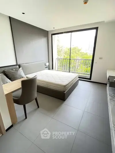 Modern bedroom with large window and balcony view, featuring minimalist decor and natural light.