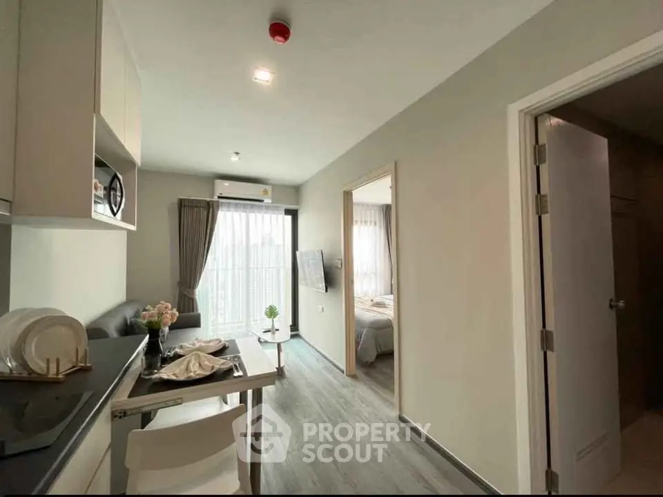 Modern apartment interior with open kitchen and cozy living area leading to a bright bedroom.