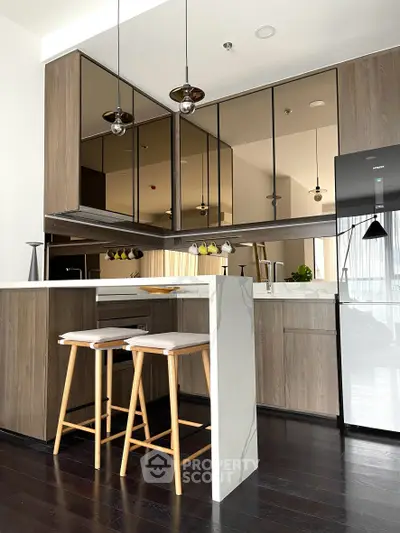 Modern kitchen with sleek design, featuring a breakfast bar, stylish pendant lights, and stainless steel appliances.