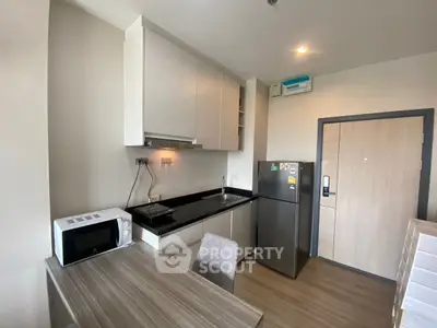 Modern compact kitchen with sleek appliances and dining area in cozy apartment.
