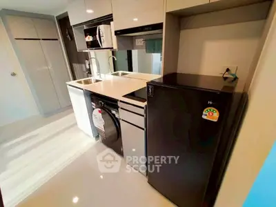 Modern kitchen with sleek appliances and glossy cabinetry in compact layout