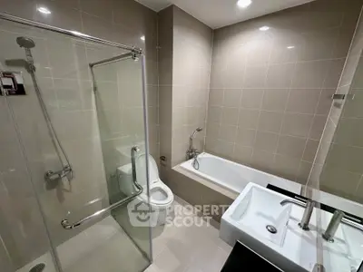 Modern bathroom with glass shower, bathtub, and sleek fixtures