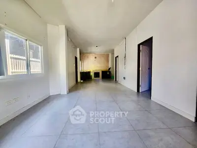 Spacious empty room with tiled flooring and large windows, ideal for customization.