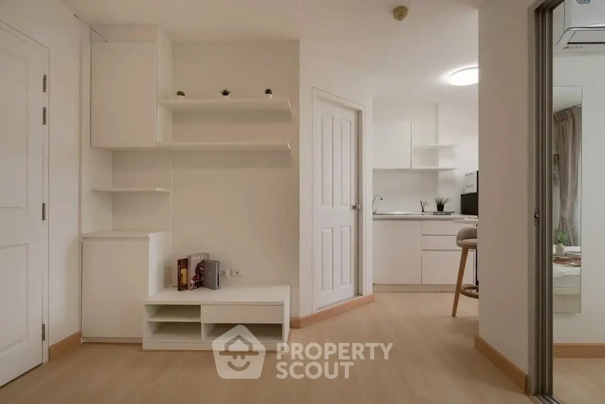 Modern minimalist apartment interior with open kitchen and sleek white cabinetry.