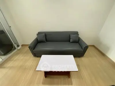 Modern minimalist living room with sleek gray sofa and wooden coffee table.