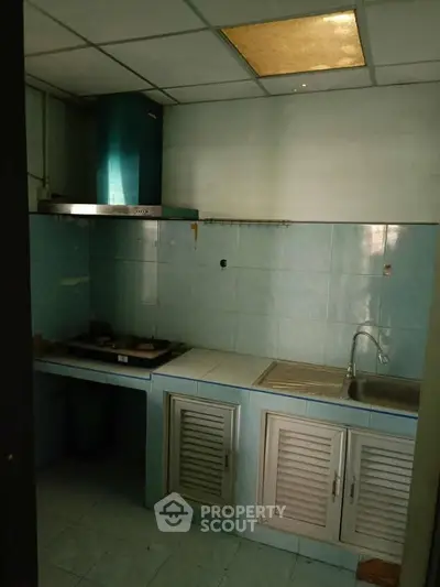 Compact kitchen with gas stove and blue tile backsplash in cozy apartment.