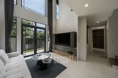 Spacious modern living room with high ceilings and large windows offering natural light and garden view.