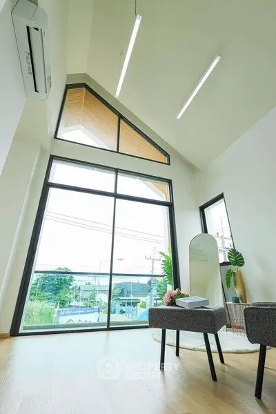 Modern living room with large windows and high ceiling, offering a bright and airy atmosphere.