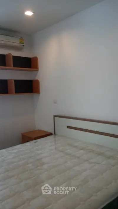 Cozy bedroom with modern design, featuring built-in shelves and air conditioning for comfort.