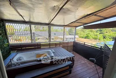 Charming balcony with rustic wooden deck and outdoor bathtub, offering serene views of lush greenery.