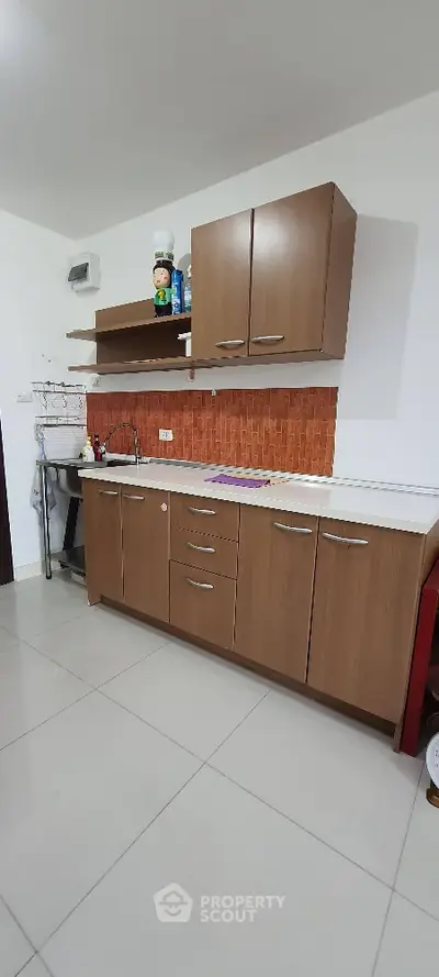 Modern kitchen with wooden cabinets and orange backsplash in a cozy apartment