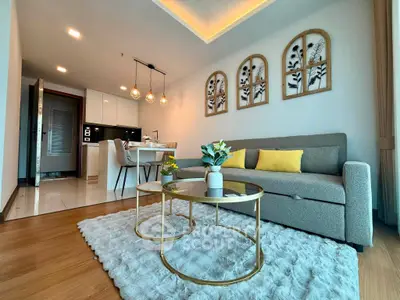 Modern living room with stylish decor and open kitchen layout, featuring cozy seating and elegant lighting.