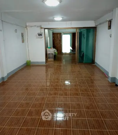 Spacious tiled room with sliding glass doors and bright lighting, ideal for versatile use in a residential property.