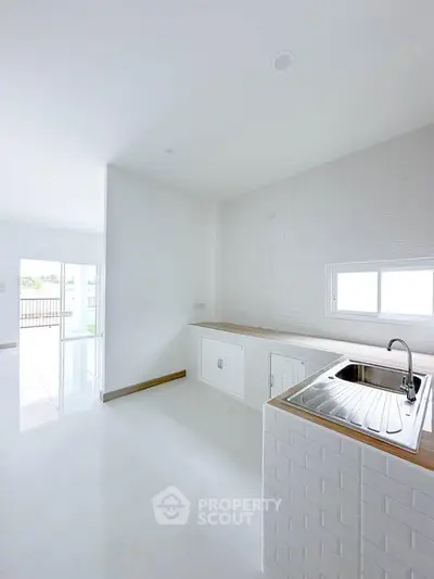 Bright modern kitchen with sleek white cabinets and stainless steel sink, featuring open layout and natural light.
