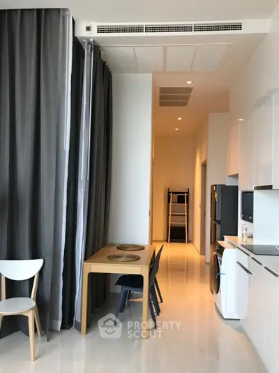 Modern kitchen with sleek design, featuring white cabinets, washing machine, and dining area with stylish chairs.