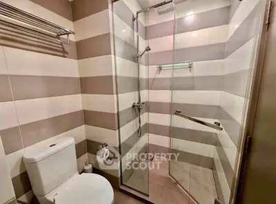 Modern bathroom with glass shower enclosure and striped tile design