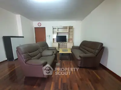 Spacious living room with leather sofas and wooden flooring, perfect for relaxation and entertainment.