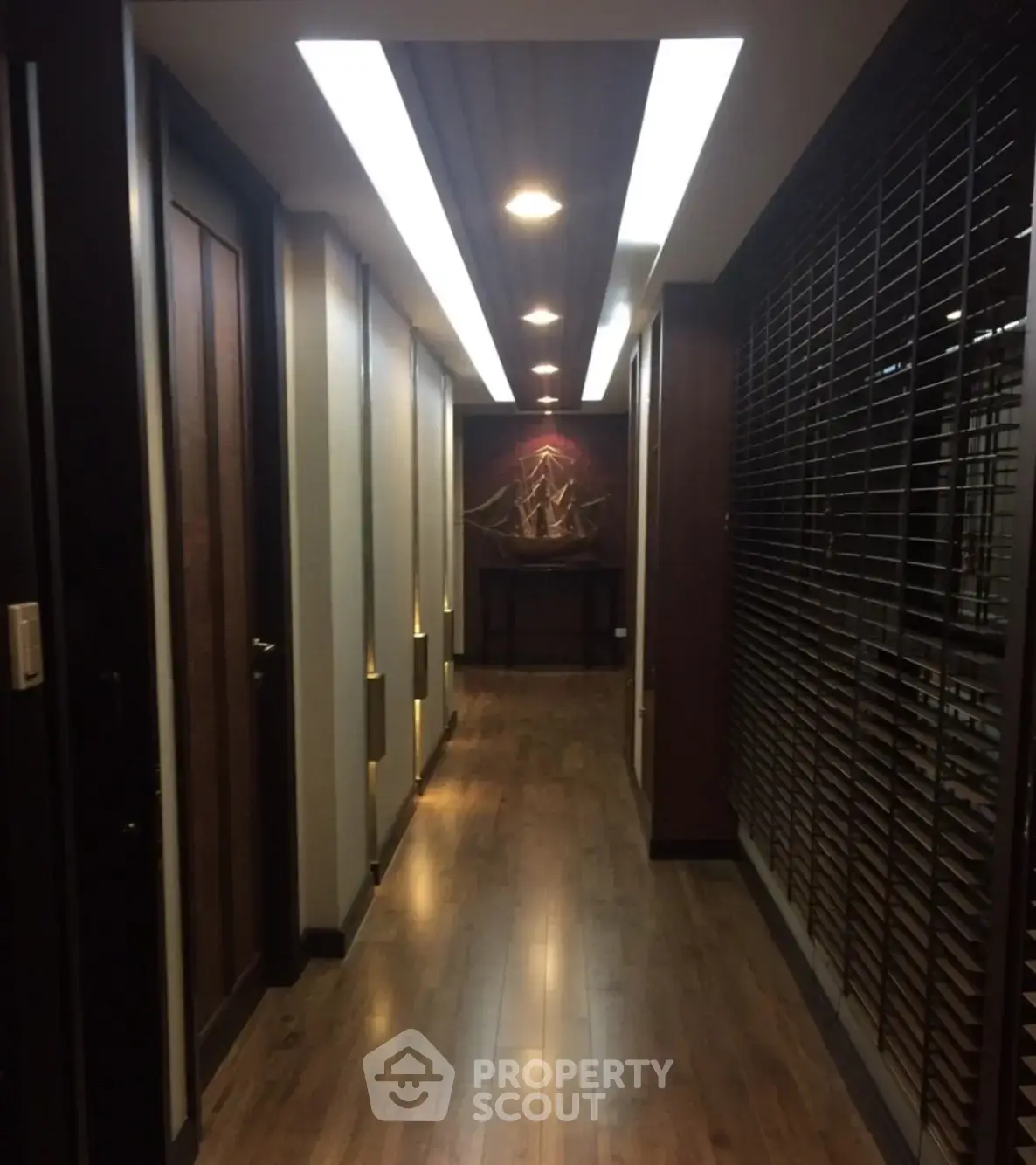 Elegant hallway with wooden flooring and modern lighting in upscale building