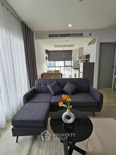 Modern living room with stylish furniture and open kitchen layout in a high-rise apartment.