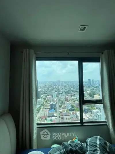 Stunning city view from a high-rise bedroom window, showcasing urban skyline and natural light.
