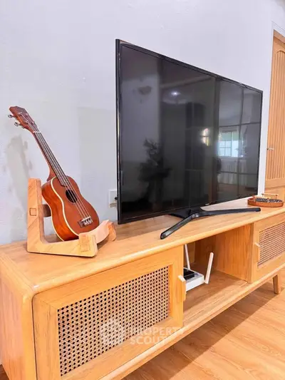 Stylish living room with modern TV stand and ukulele, perfect for cozy entertainment.
