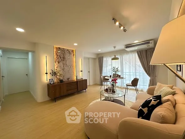 Spacious living room with elegant decor and natural light, featuring a cozy sofa and stylish lighting.