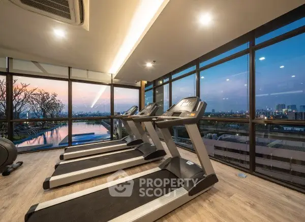 Luxurious gym with treadmills and stunning city view at sunset