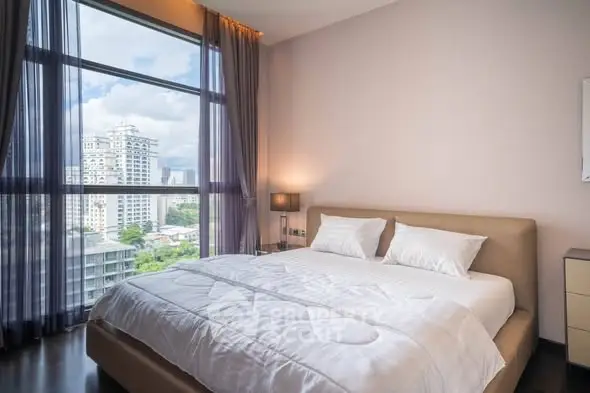 Luxurious bedroom with large window offering stunning city views in a modern high-rise apartment.
