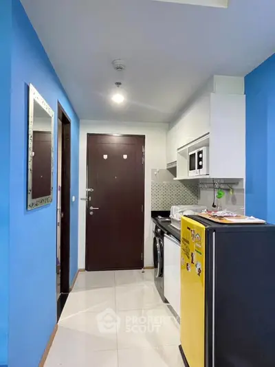 Compact modern kitchen with blue walls and stylish appliances in urban apartment
