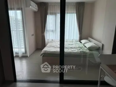 Modern bedroom with large windows and balcony access in a stylish apartment.