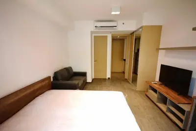 Modern bedroom with minimalist design, featuring a cozy bed, sleek TV setup, and comfortable seating area.