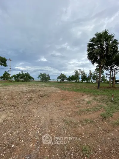 Expansive vacant land with lush greenery and clear skies, perfect for development opportunities.