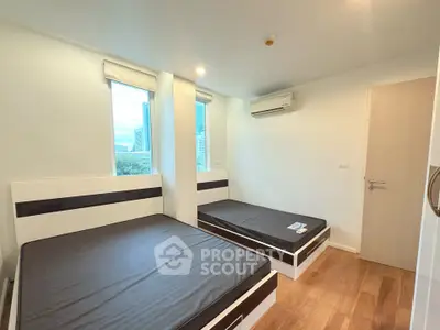 Modern bedroom with twin beds and city view, featuring sleek design and ample natural light.