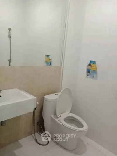 Modern bathroom with sleek fixtures and minimalist design, featuring a toilet and sink.