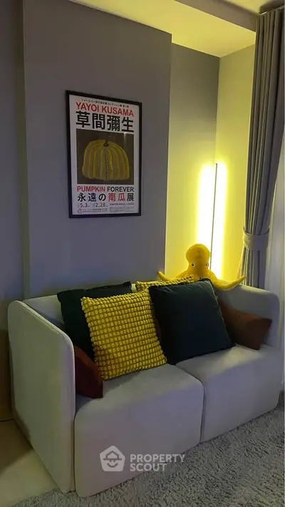 Cozy living room with modern sofa, colorful cushions, and stylish wall art, perfect for relaxation.