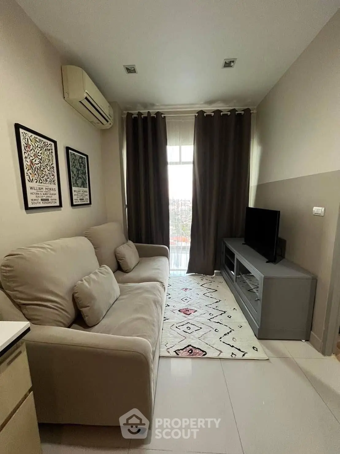 Cozy living room with modern decor and natural light, featuring a comfortable sofa and flat-screen TV.