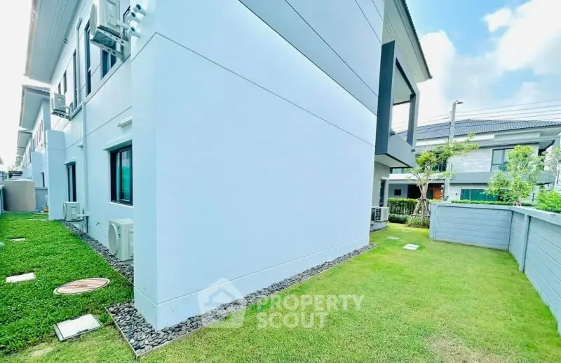 Modern residential building with lush green lawn and sleek exterior design.