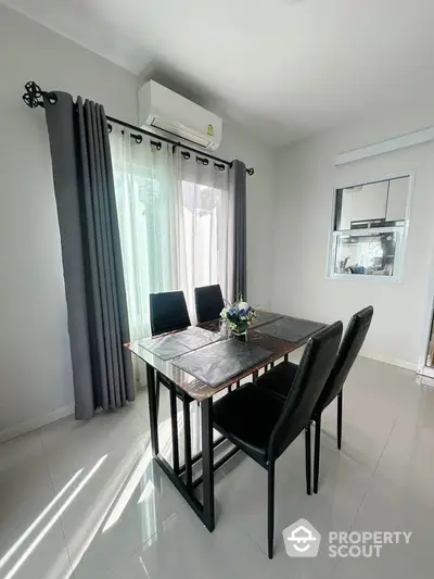 Modern dining area with sleek black chairs and table, bright natural light, and elegant curtains.