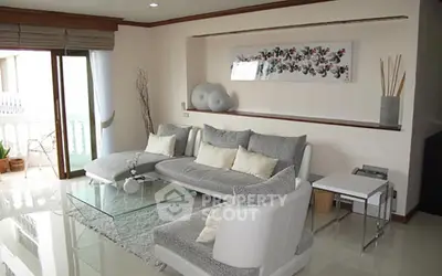 Elegant living room with modern decor and large windows opening to a balcony, perfect for relaxation.
