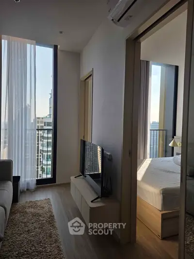 Modern apartment with cozy living room and bedroom, featuring large windows and a balcony view.