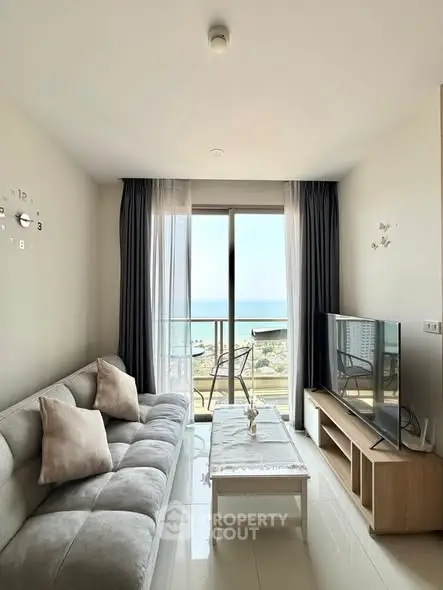 Modern living room with ocean view, cozy sofa, and large TV, perfect for relaxation and entertainment.