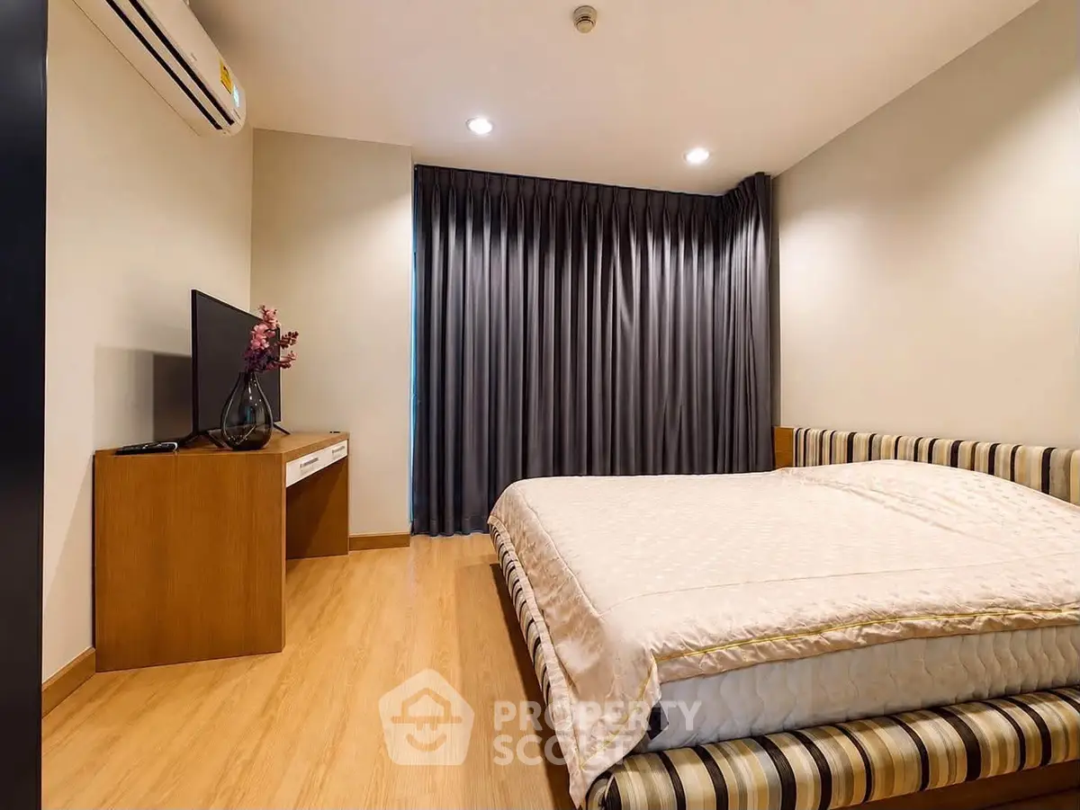 Cozy bedroom with modern decor, featuring a comfortable bed, TV, and elegant curtains.