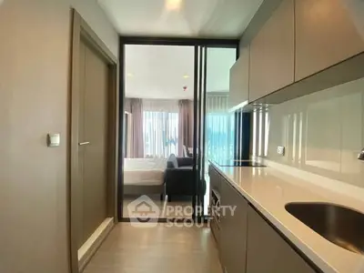 Modern apartment kitchen with sleek cabinetry and open view to bedroom