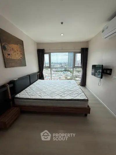 Spacious bedroom with city view, featuring a large bed and wall-mounted TV, perfect for urban living.