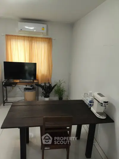 Cozy study room with wooden desk, TV, and air conditioning, perfect for productivity.