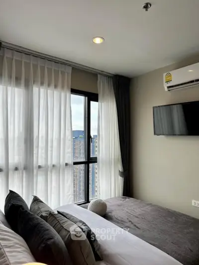 Modern bedroom with city view, featuring stylish decor and natural light.