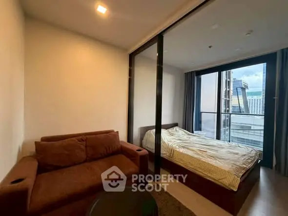 Modern studio apartment with cozy living area and city view balcony.