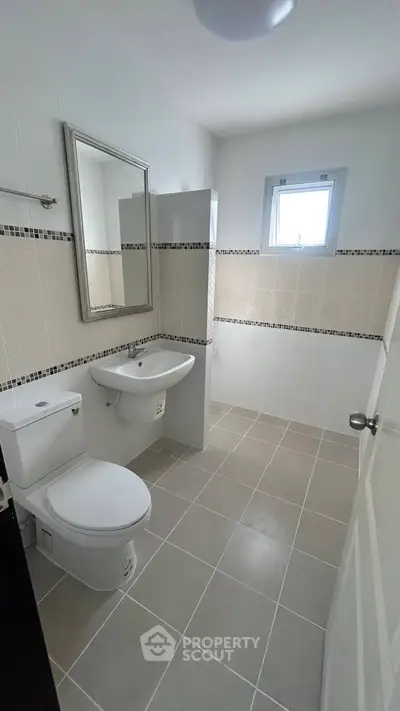 Modern bathroom with sleek fixtures and neutral tiles, featuring a large mirror and natural light.