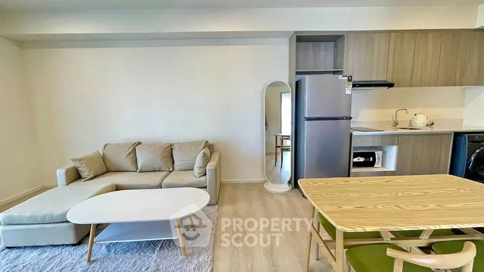 Modern open-plan living room with cozy sofa and sleek kitchen area in stylish apartment.